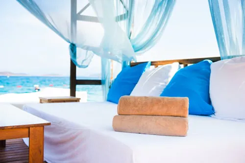 Freshly cleaned coastal bedroom with white linens and blue pillows